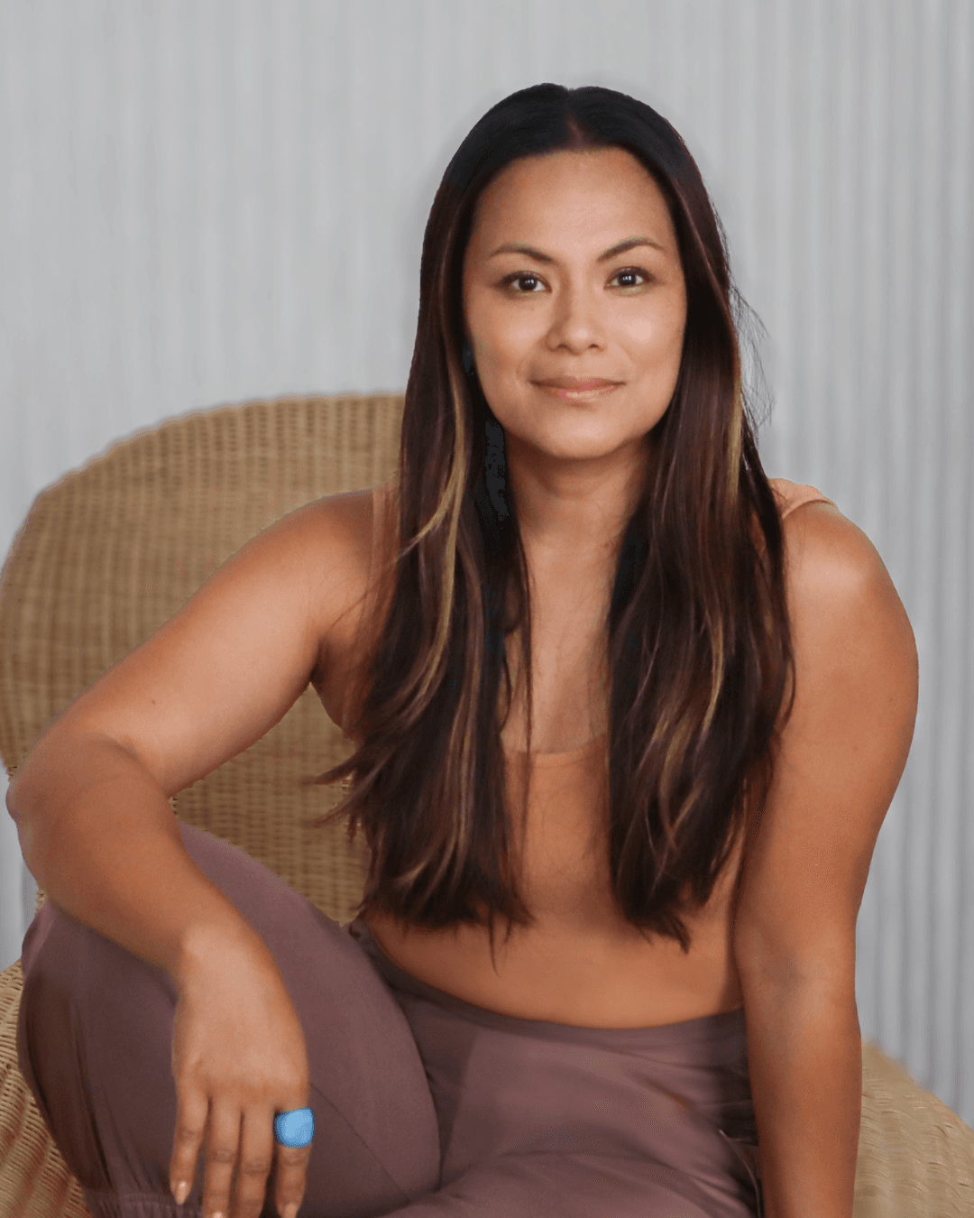 Blessyl Buan, seated in a woven chair, radiates calm strength wearing soft earth tones.